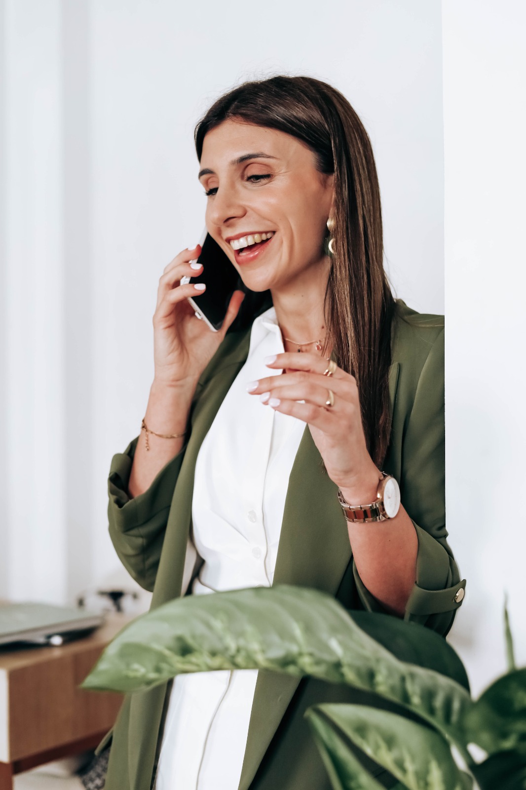 Flávia Santos ao telefone, com blazer verde-oliva.